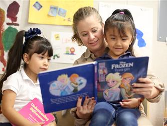 teacher reading to two young students