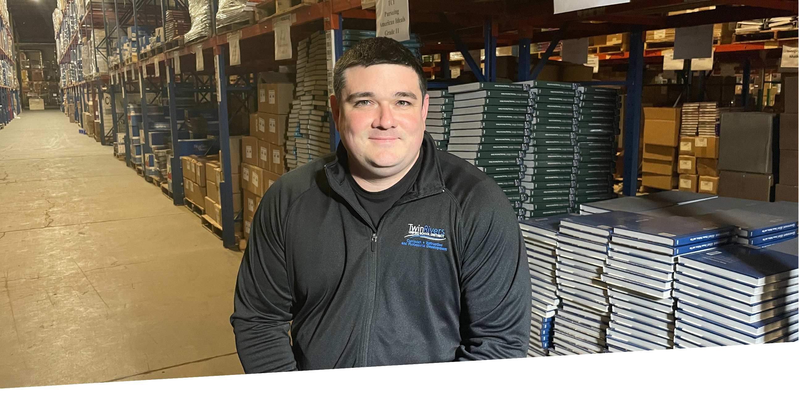 man sitting in warehouse in front of instructional materials on racks