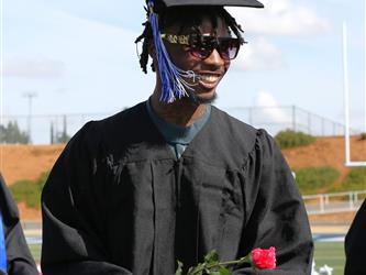 high school student holding a rose, diploma and smiling.