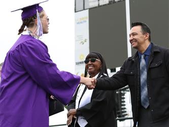 high school graduate shaking hands with superintendent.