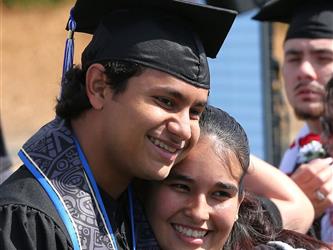 high school graduate smiling and hugging family member. 