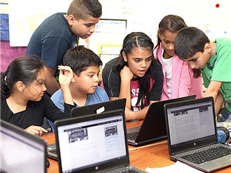 students gathered around laptop