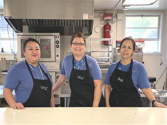 cafeteria servers in school standing and smiling.