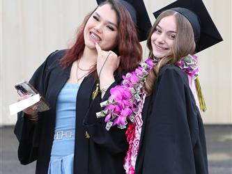 Two High school graduates smiling.