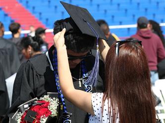 family member adjusting high school graduates cap.