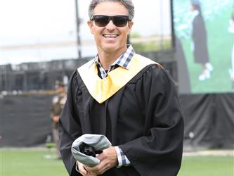 Staff member at high school graduation smiling with sunglasses on.