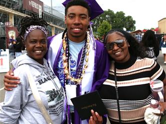 high school graduate posing with family members.