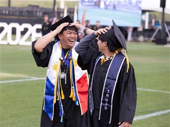 two high school graduates smiling