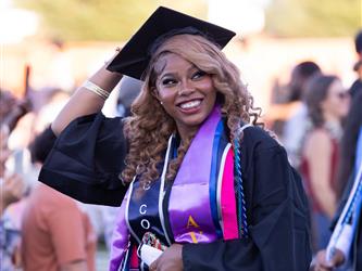 female high school graduate in cap and gown smiling