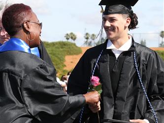 high school student smiling and receiving a rose for graduation.