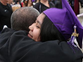 high school graduate hugging familiy member.