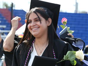 high school student smiling and holding a rose and diploma.