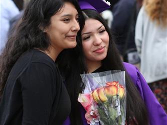 high school graduate posing with family member.
