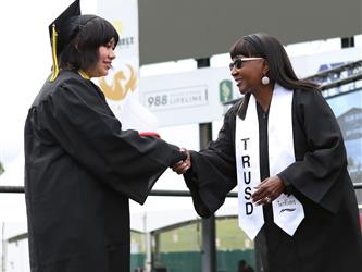 High school graduate shaking hands with a member of the board of trustees.
