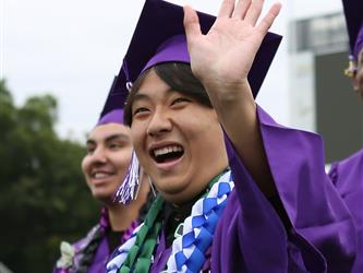 high school graduate smiling and waving.