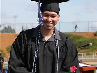 high school student smiling and receiving a rose for graduation.