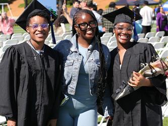 Two Adult Education graduates smiling brightly with family member.