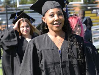Adult Education graduate smiling brightly at graduation ceremony.