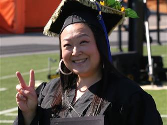 Adult Education graduate smiling brightly at graduation ceremony.