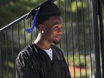 Adult Education graduate smiling brightly at graduation ceremony.