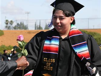 high school student smiling and receiving a rose for graduation.