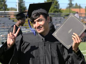 Adult Education graduate smiling brightly at graduation ceremony.