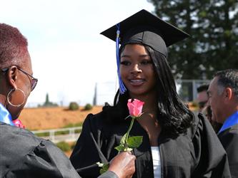 high school student smiling and receiving a rose for graduation.