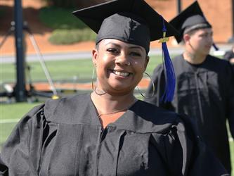 Adult Education graduate smiling brightly at graduation ceremony.