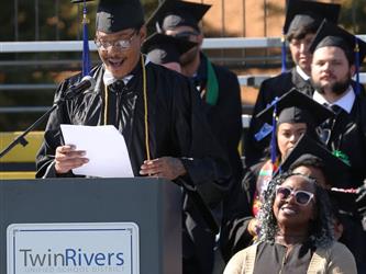 Adult Education graduate giving speech at graduation ceremony.