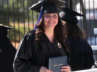 Adult Education graduate smiling brightly at graduation ceremony.