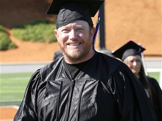Adult Education graduate smiling brightly at graduation ceremony.