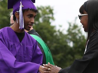 high school graduate shaking hands with board of trustees president.