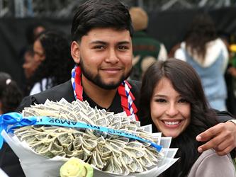 High school graduate smiling while hugging girlfriend.