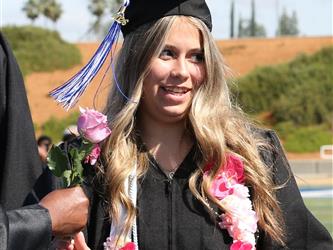 high school student holding a rose and smiling.