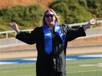 high school staff member smiling while arms are extended.