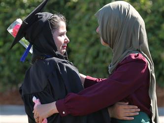 Adult Education graduate hugging family member at graduation ceremony.