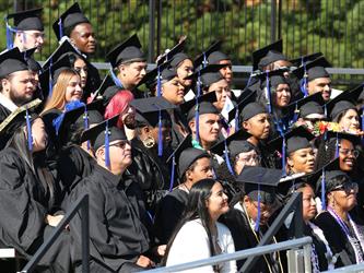 Adult Education graduates sitting in stands looking into the crowd seated below.