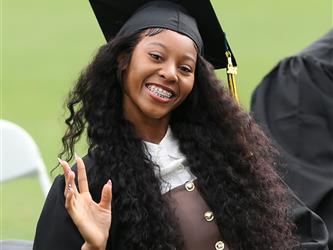 High school graduate smiling and waving.
