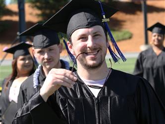 Adult Education graduate smiling brightly at graduation ceremony.