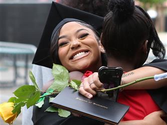 High school graduate smiling while hugging a family member.
