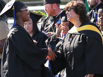 Adult Education graduate shaking hands with a school board trustee.