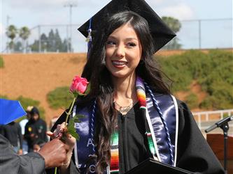 high school student smiling and receiving a rose for graduation.