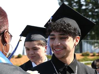 high school student smiling and receiving a rose for graduation.