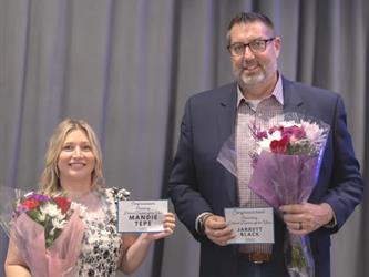 two teachers standing and holding flowers after receiving award.