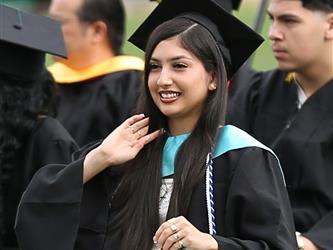 High school graduate smiling and waving.