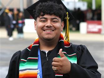 High school graduate smiling with a thumbs up sign.