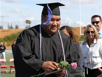 high school student smiling and receiving a rose for graduation.