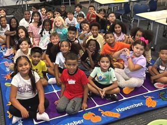 elementary students sitting on rug in classroom