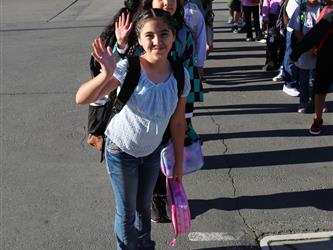 elementary student smiling and waving