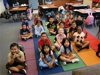 kindergarten students sitting on carpet in classroom